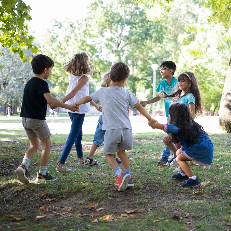Group of children, arm in arm playing outside in a circle